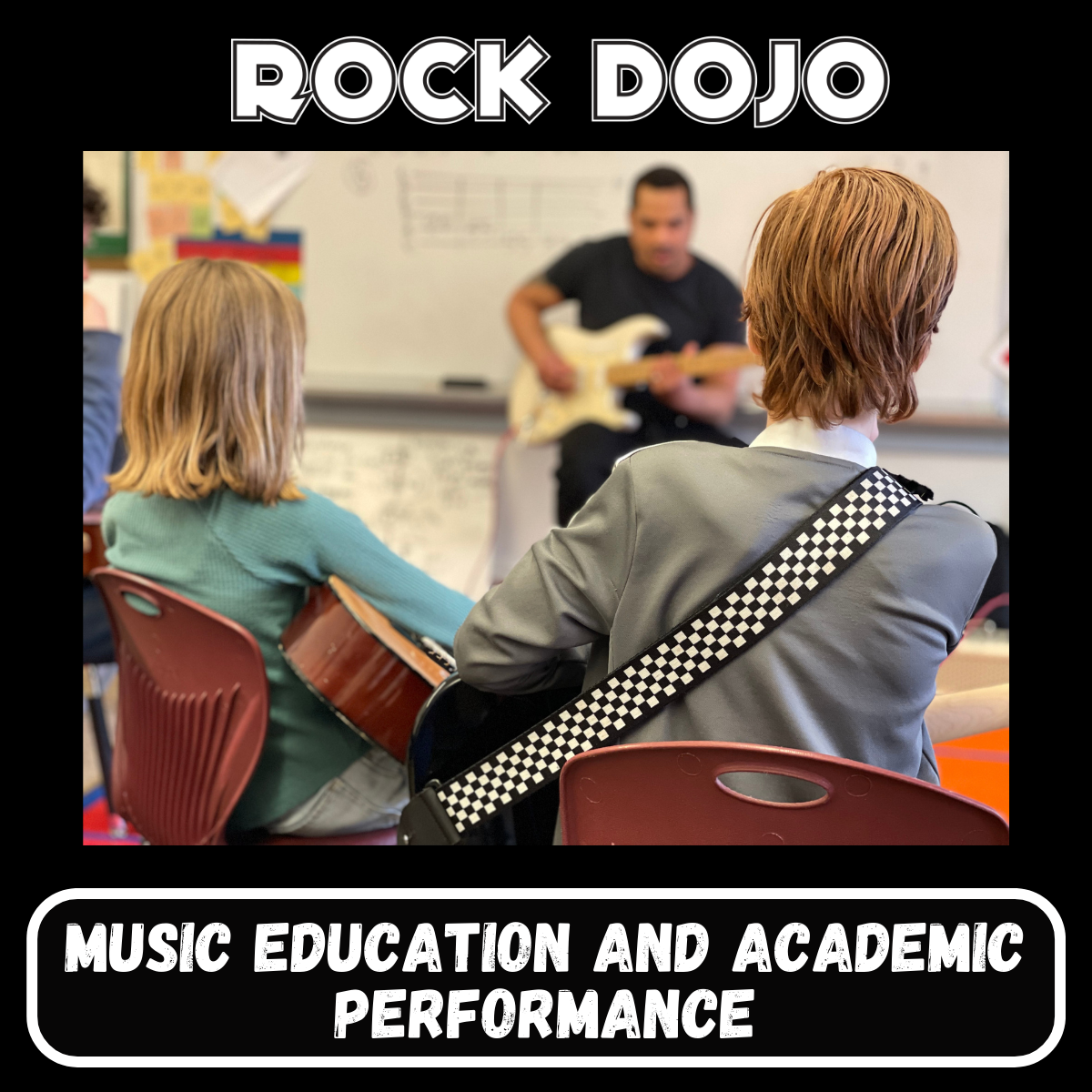 Children seating in a classroom during a Rock Dojo Guitar After-School class are focusing on the teacher demonstrating a concept on the guitar