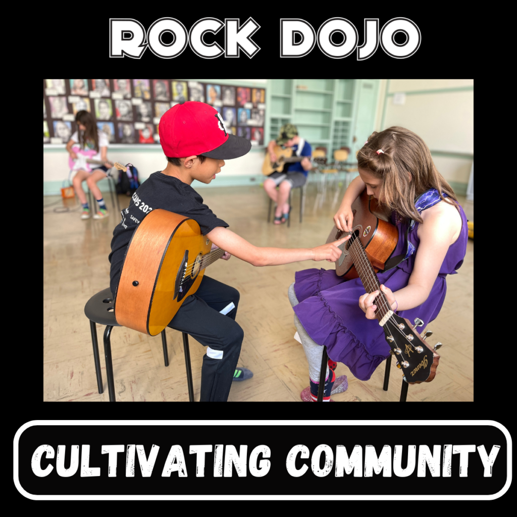 Boy pointing at a part of his guitar while teaching a younger girl during Rock Dojo's guitar lessons for kids.