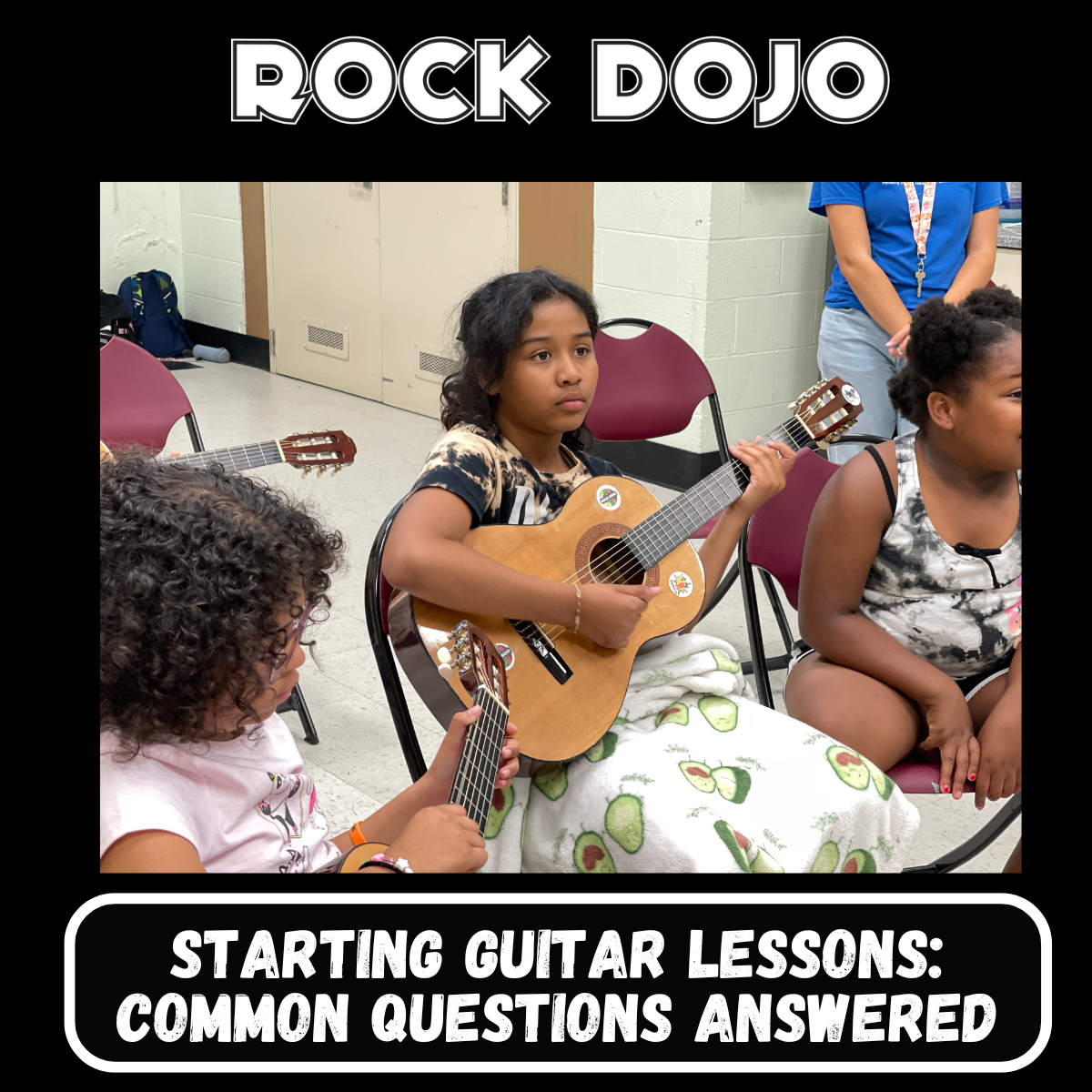 Children learning to play the guitar in a Rock Dojo classroom, highlighting the start of their guitar lessons journey.